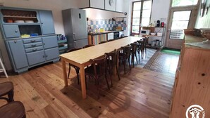 Eine Küche mit Holztisch und -stühlen, einem blauen Schrank und einem Fenster.