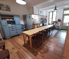 Uma cozinha com mesa e cadeiras de madeira, um armário azul e uma janela.