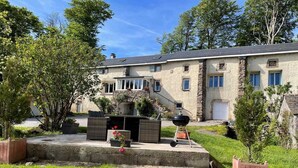 A two-story stone building with a patio area featuring outdoor furniture and a barbecue grill. - Ferme les Taillades 2-4 persons (CAMBON ET SALVERGUES)