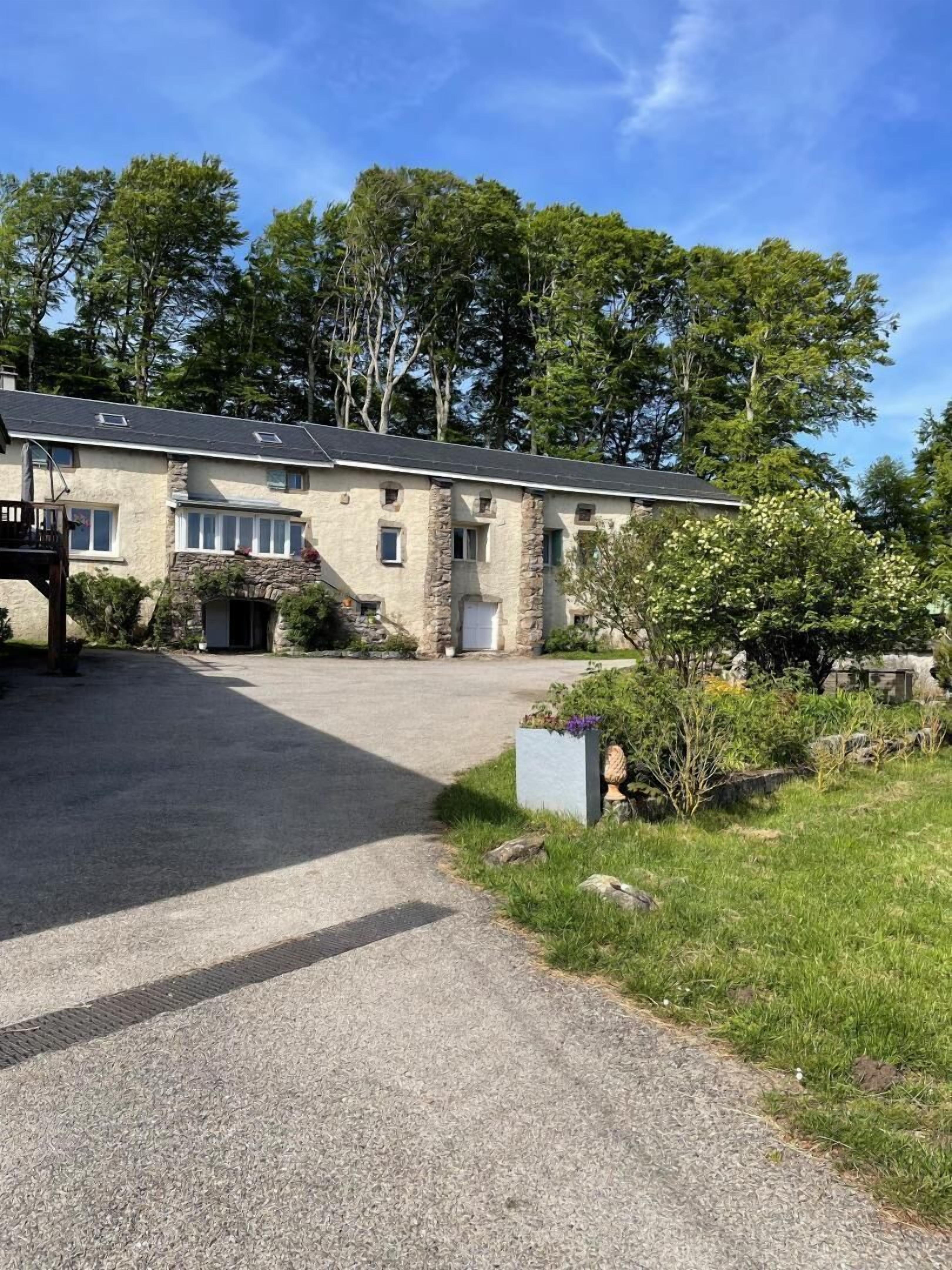 A two-story stone building with a gravel driveway leading to a front door.