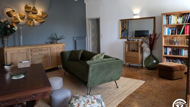 A cozy living room with a green sofa, wooden coffee table, and a bookshelf filled with books. - Ferme les Taillades 2-4 persons (CAMBON ET SALVERGUES)