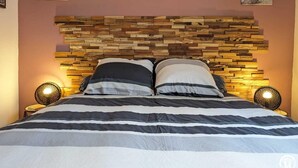 A bed with a wooden headboard, two bedside lamps, and three wall-mounted floral paintings. - L'Arcolan - VALRAS PLAGE (VALRAS PLAGE)
