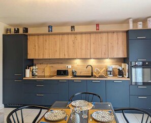A modern kitchen with dark cabinets, a wooden countertop, and a dining area with a table set for two.