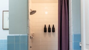A bathroom with a shower, a toilet, and a sink. There are three bottles of shampoo on the wall. - Stylish UM Loft on Diag (Ann Arbor)