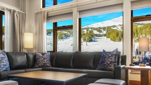 Una sala de estar moderna con un sofá modular, una mesa de centro y vistas a una estación de esquí.