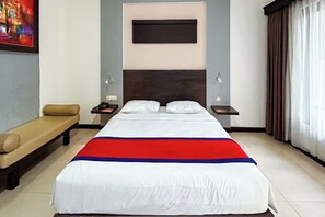 A hotel room with a large bed, a bench, a nightstand, and a painting on the wall. - Ozz Hotel Kuta Bali manage by Ozz Group (Bali)