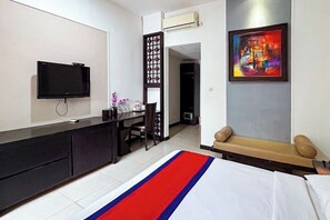 A hotel room with a bed, a desk, a TV, a painting, and a massage chair. - Ozz Hotel Kuta Bali manage by Ozz Group (Bali)