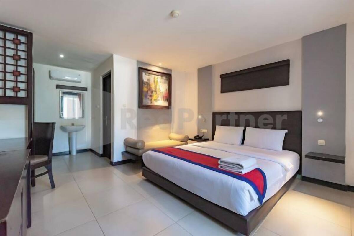 A modern hotel room with a large bed, a desk, and a chair.