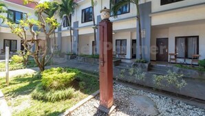 A modern building with multiple balconies, a central courtyard with plants, and a stone pathway. - Ozz Hotel Kuta Bali manage by Ozz Group (Bali)