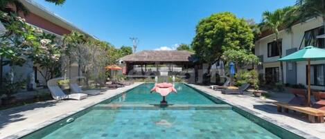 A swimming pool with lounge chairs and a gazebo in a resort setting.