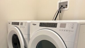 A front-loading Whirlpool washer and dryer in a laundry room with a tiled floor and a power outlet on the wall. - Clean and Spacious 4-bdrm Family home in Whitby! (Whitby)