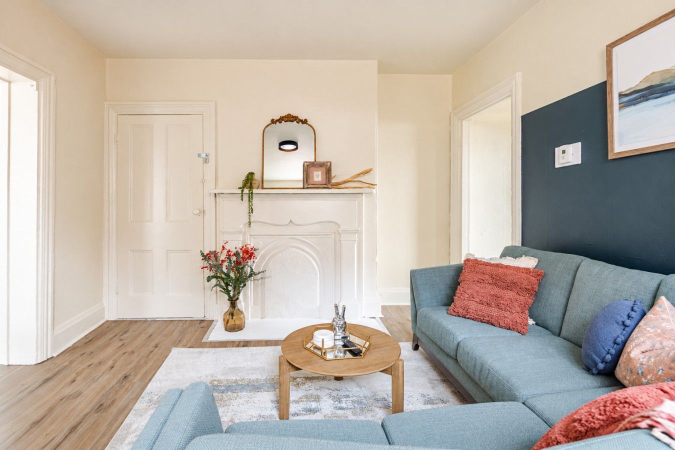 Un salon avec un canapé, une table basse, une cheminée et un miroir.
