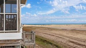 Uma casa de praia com um deck de madeira e vista para a praia e o oceano.