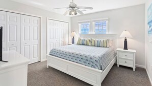 Quarto com uma cama, duas mesas de cabeceira, um ventilador de teto e uma janela com vista.
