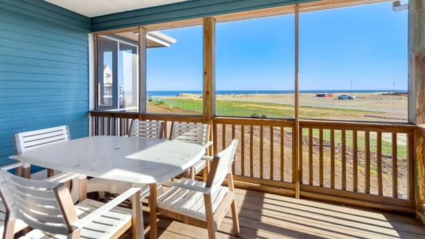 A covered outdoor area with a table and chairs, a view of the beach, and a clear sky. - Whelk – Dog-Friendly & Steps from Buxton Beach (Buxton)