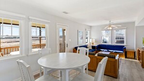 A spacious living area with a round table and chairs, a blue sofa, and a ceiling fan. - Barracuda: Cozy Buxton Getaway w/ Ocean Views (Buxton)