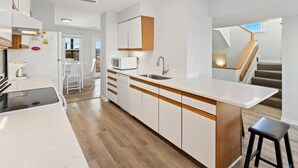 A modern kitchen with white cabinetry, a wooden countertop, and a built-in microwave. - Barracuda: Cozy Buxton Getaway w/ Ocean Views (Buxton)