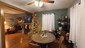 Un comedor acogedor con una mesa y sillas de madera, un árbol de Navidad y una chimenea.