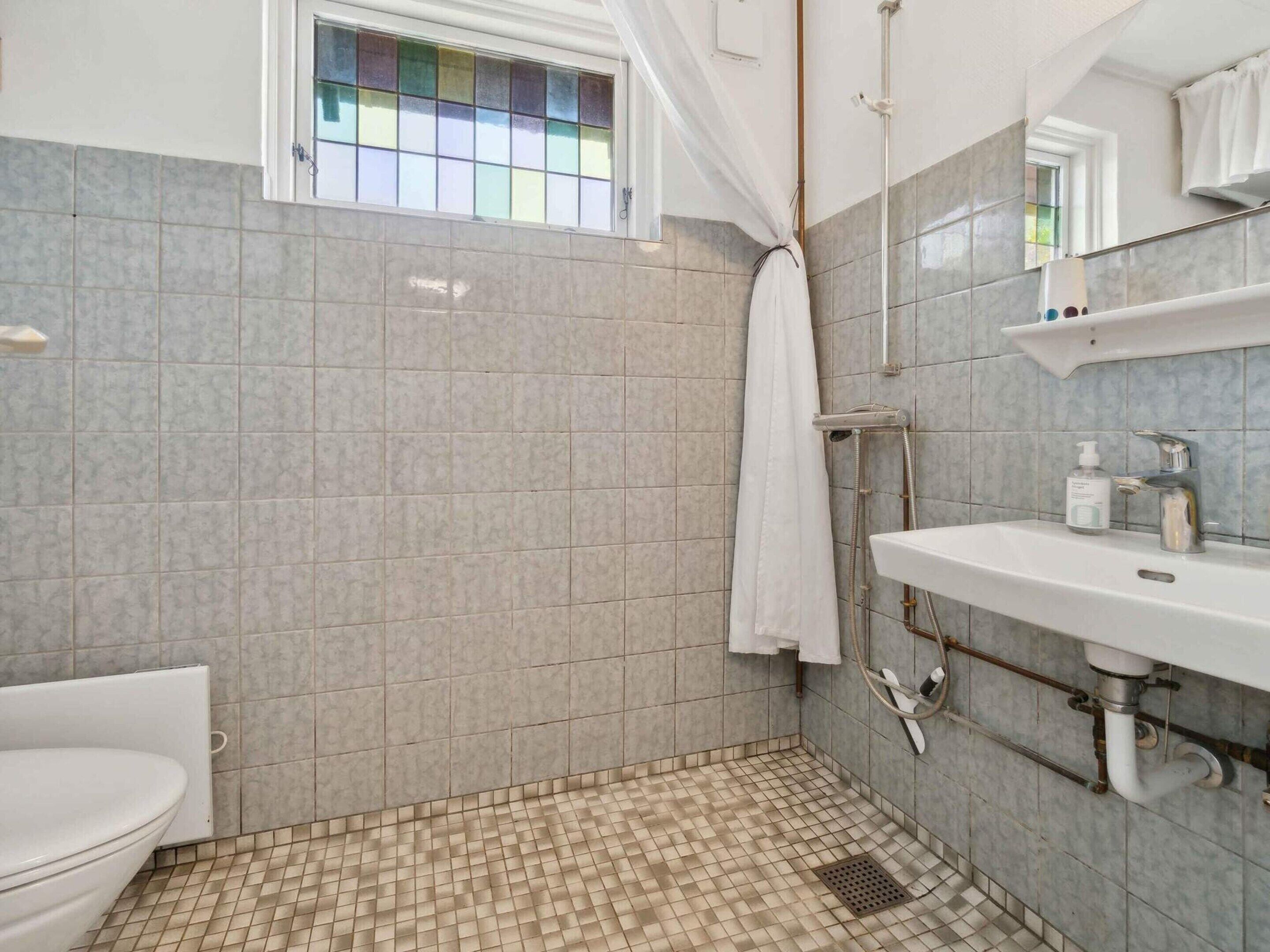 A bathroom with a shower, toilet, and sink.