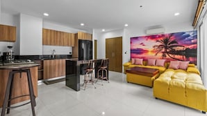 Una cocina moderna con armarios de madera, un refrigerador negro y una zona de bar con taburetes.