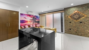 Una cocina moderna con una isla central, un cuadro grande de una puesta de sol, una pared de acento de piedra y un amplio ventanal corredizo.