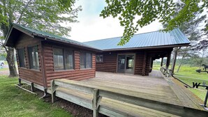 A log cabin with a covered deck and a door leading to an interior space.
