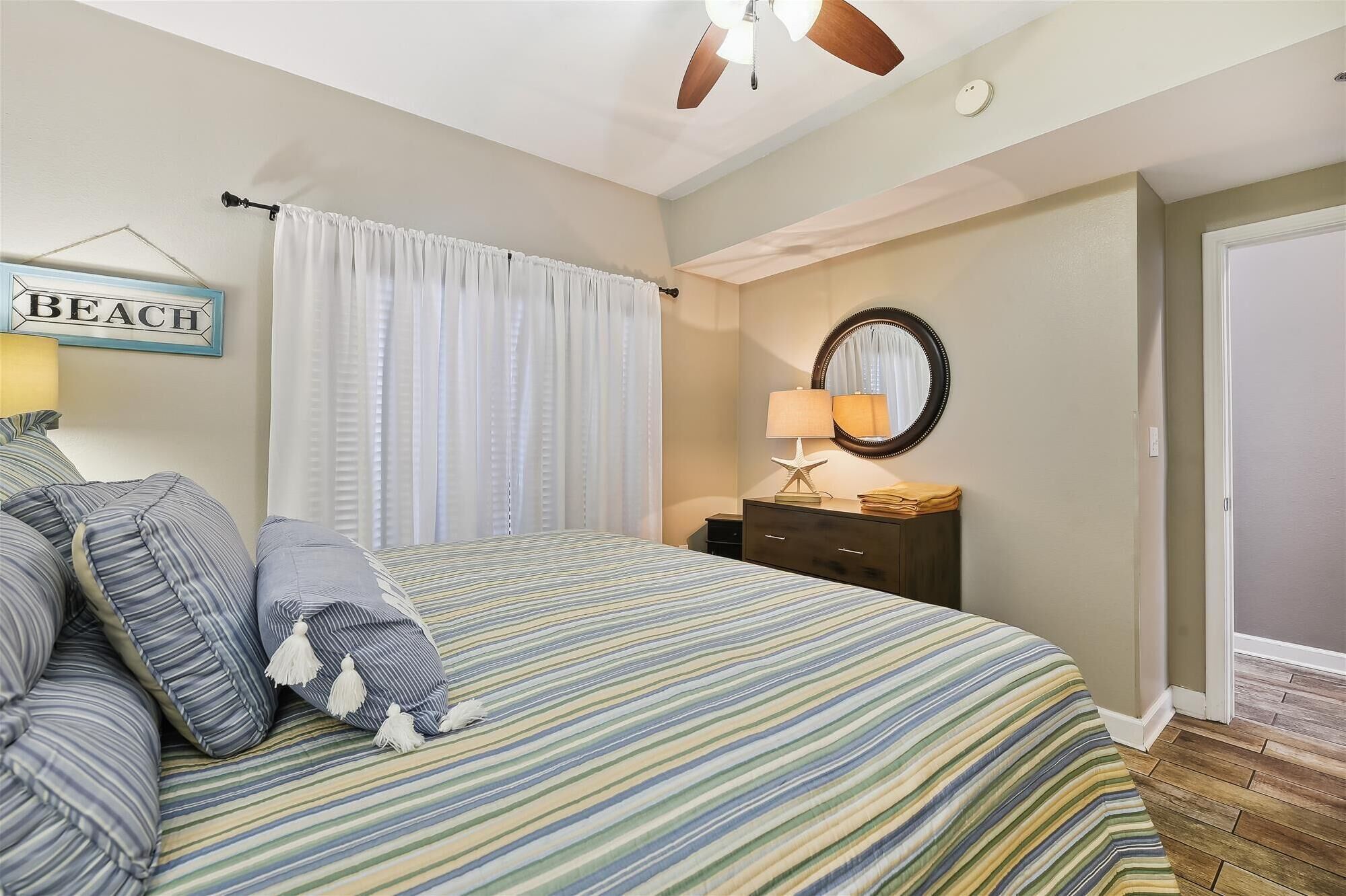 Un dormitorio con cama, cómoda, espejo, lámpara con forma de estrella de mar y un cartel que dice 'BEACH'.
