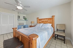 A bedroom with a wooden bed, a chair, a desk, and a ceiling fan. - Riverfront Pool Home w/ Dock & Tennis Access (Cocoa Beach)
