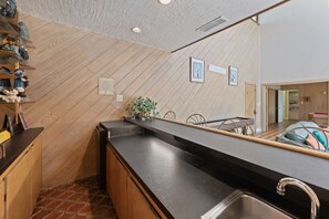 Una cocina moderna con piso de madera en patrón de espiga, encimera negra y pileta de acero inoxidable.