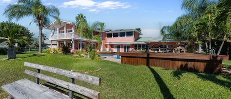 Un quartier résidentiel avec une grande maison, une piscine et une terrasse en bois.