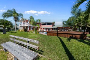 A residential area with a large house, a pool, and a wooden deck.