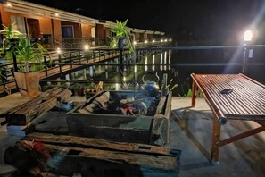 A rooftop terrace with a wooden table, potted plants, and a pool. - Monthatip vill (Chom Thong)