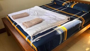 A bed with a blue and yellow striped bedspread, two beige towels, and matching pillows. - Monthatip vill (Chom Thong)