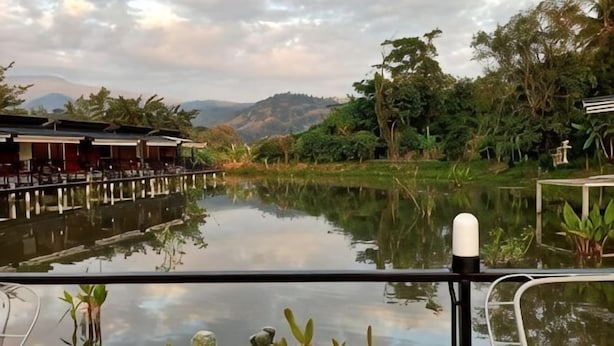 A riverside view with a dining area, potted plants, and a calm water body. - Monthatip vill (Chom Thong)