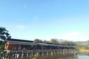 A row of buildings with a water body in the foreground. - Monthatip vill (Chom Thong)