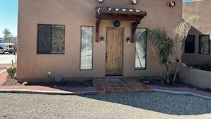 A modern building with a wooden door, large windows, and a small patio area with plants.