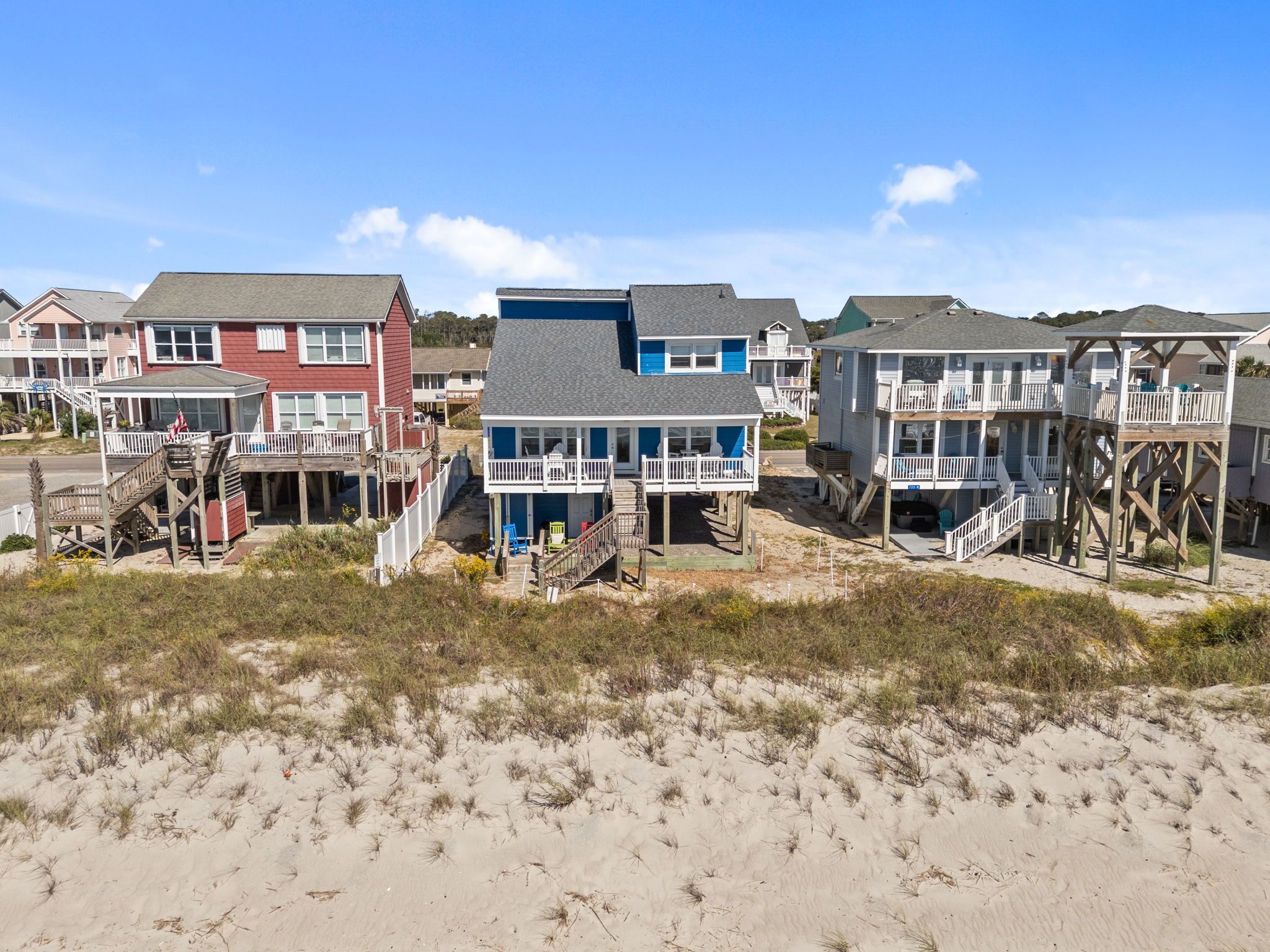 Una propiedad frente a la playa con varias casas, cada una con balcón y escalera que da a la playa.