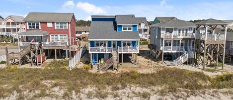 Una propiedad frente a la playa con varias casas, cada una con balcón y escalera que da a la playa.