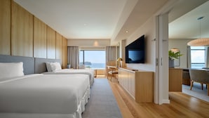 Une chambre d’hôtel avec deux lits, un bureau, une télévision et une vue sur la mer.