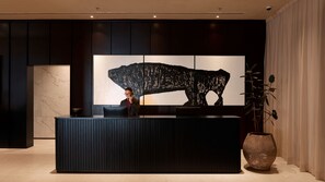 A reception desk with a large abstract artwork, a security camera, and a potted plant. - Ormond Sandakan (Sandakan)