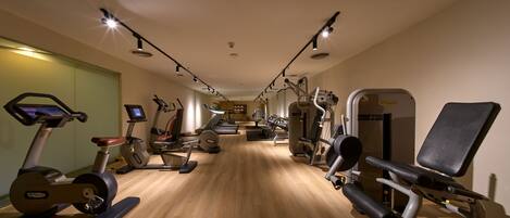 A gym with cardio machines, weightlifting equipment, and a mirror wall.