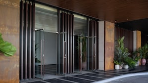 Une entrée moderne avec des portes en verre, des barreaux métalliques verticaux et des plantes en pot.