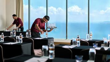 A conference room with tables set for a meeting, water bottles, and a view of the ocean through large windows.