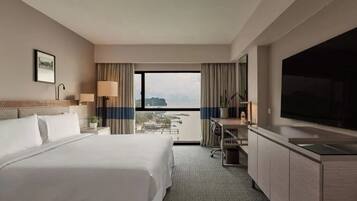 Habitación de hotel con cama, escritorio, televisión y vista a la ciudad.