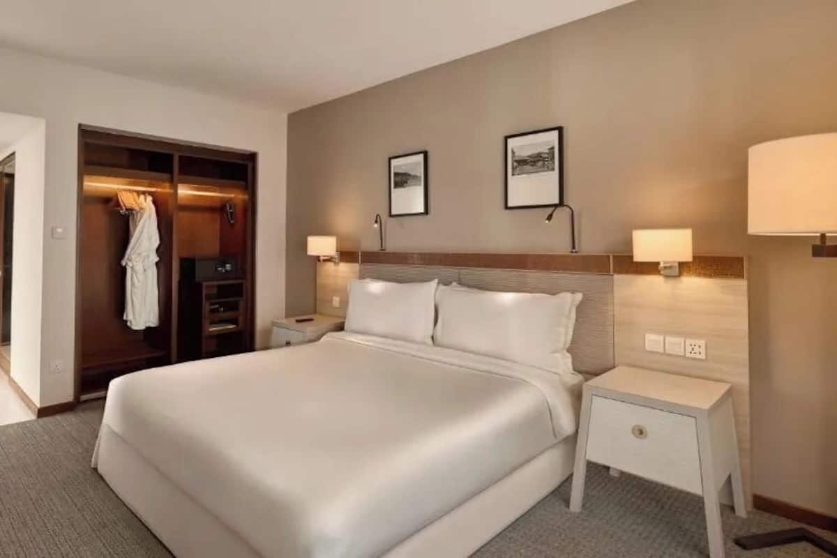 A hotel room with a large bed, a walk-in closet, two bedside lamps, and a nightstand.