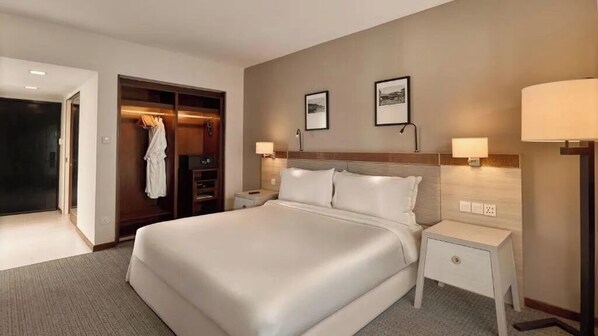 A hotel room with a large bed, a walk-in closet, two bedside lamps, and a nightstand. - Ormond Sandakan (Sandakan)