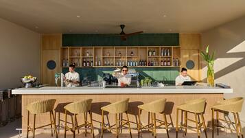 A bar area with a counter, bar stools, and shelves of bottles.