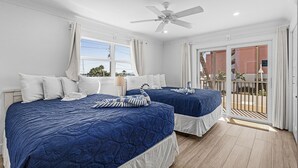 Een hotelkamer met twee bedden, een plafondventilator en een balkon met uitzicht.