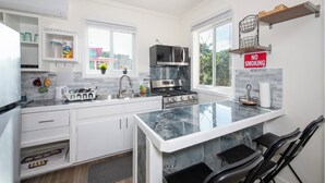 Una cucina moderna con mobili bianchi, un'isola grande con piano di lavoro in marmo, elettrodomestici in acciaio inossidabile e un cartello con la scritta 'NO SMOKING'.