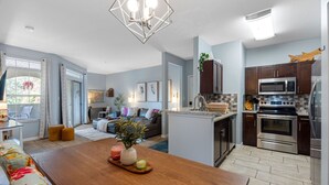 Una cocina moderna con electrodomésticos de acero inoxidable, un comedor con mesa de madera y una sala de estar con sofá y mesa de centro.